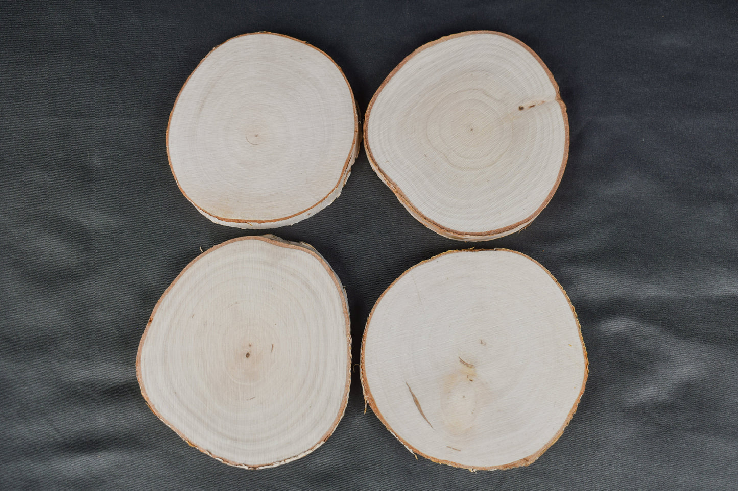 A set of four birch wood coasters laying on a gray surface