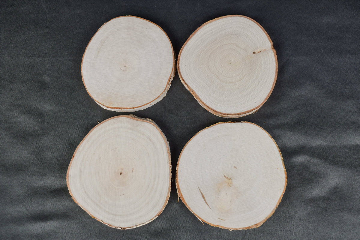 A set of four birch wood coasters laying on a gray surface