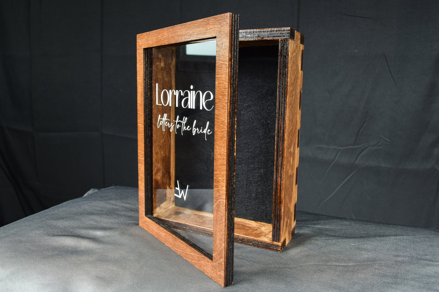 A handcrafted wooden letter box showcasing the hinged lid and clear cover, featuring a custom engraving of 'Lorraine letters to the bride' in white and a black felt lined interior