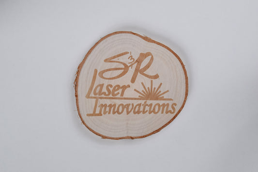 a birch coaster with S&R laser innovations logo engraved on it, against a white background
