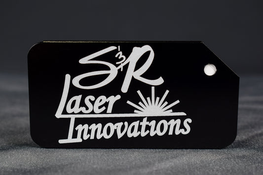 A black aluminum luggage tag with the 'S&R Laser Innovations' logo laser engraved on the front