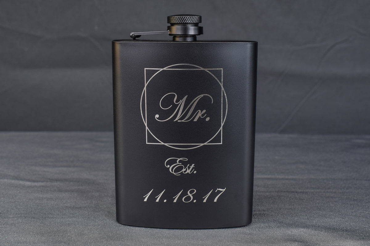 a black flask engraved with "Mr. Established 11/18/17" against a dark background