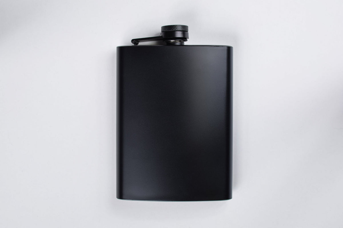 A black metal flask lying on a white background