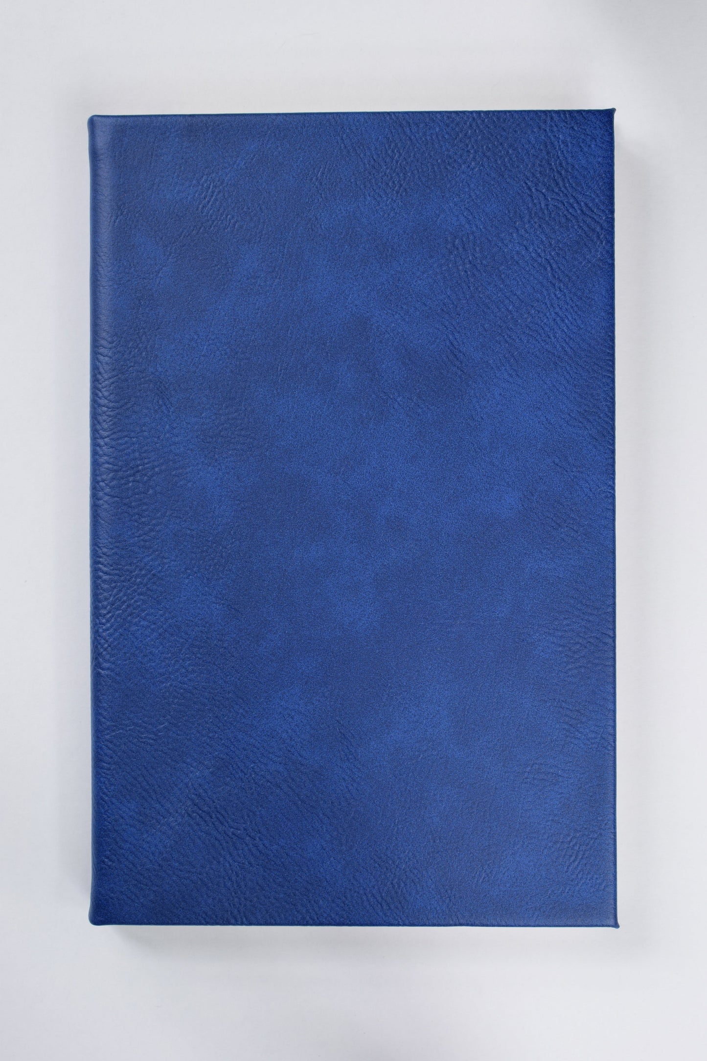 a blue leatherette journal lying on a white surface