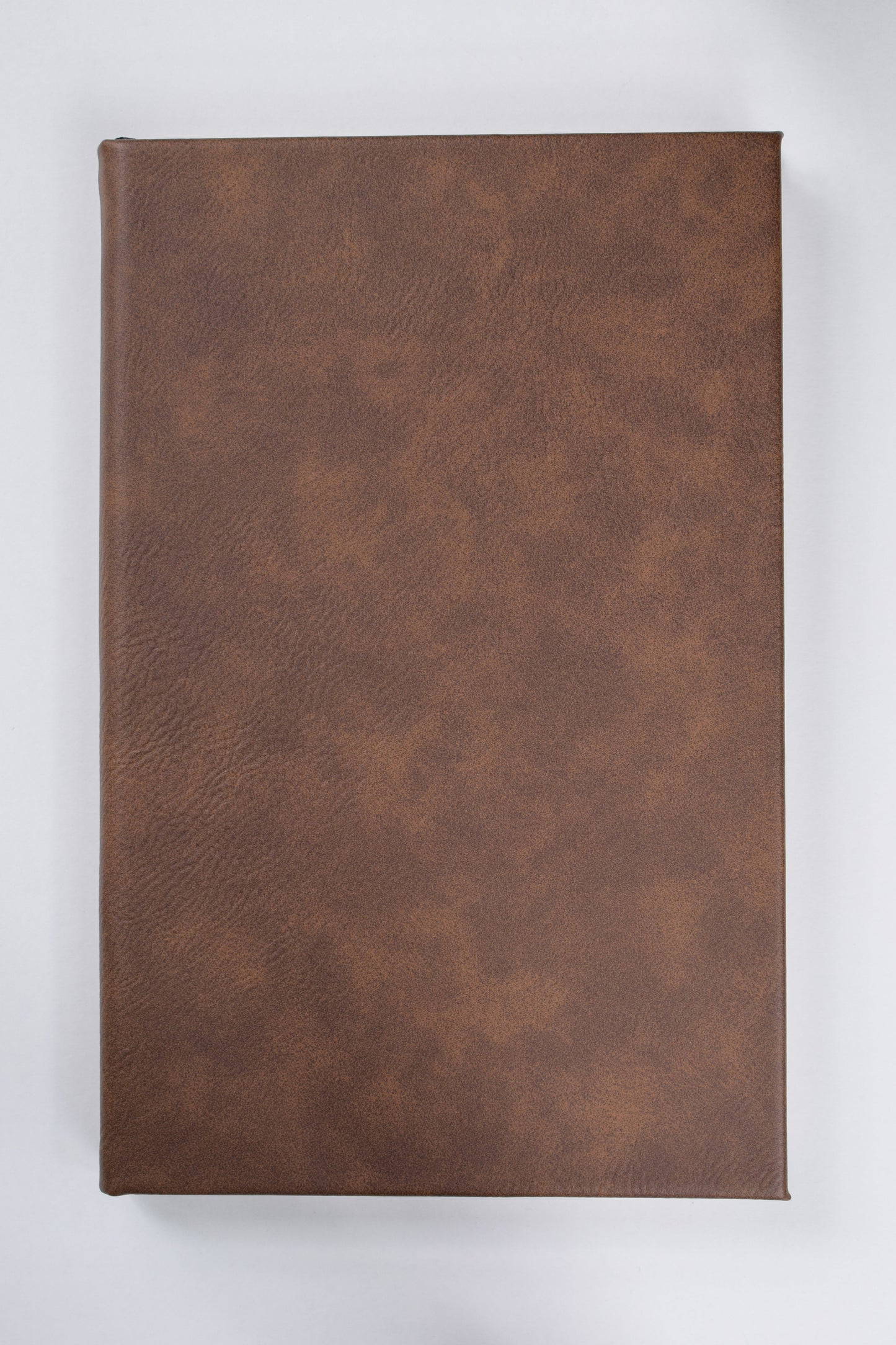 a dark brown leatherette journal lying on a white surface