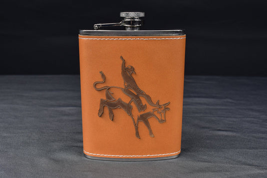 a leather wrapped steel flask with a custom engraving of a bull rider, against a black and gray background