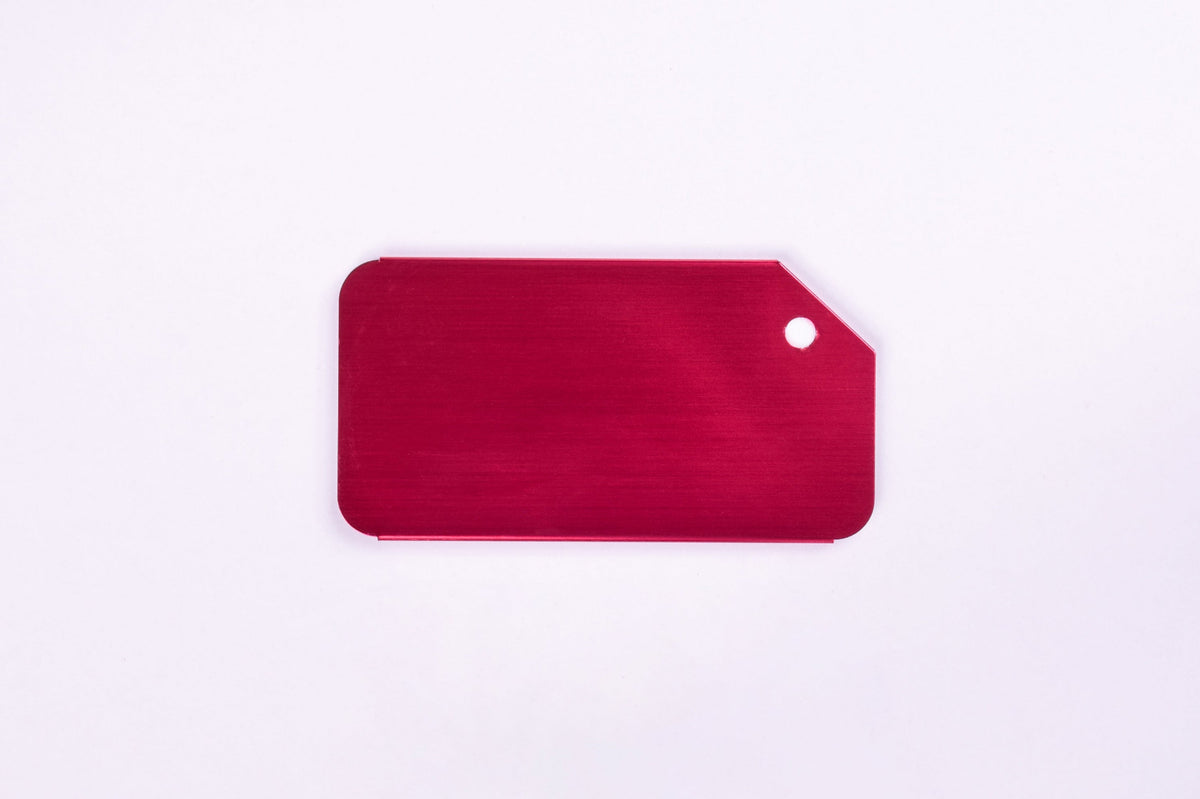 A magenta aluminum luggage tag on white background