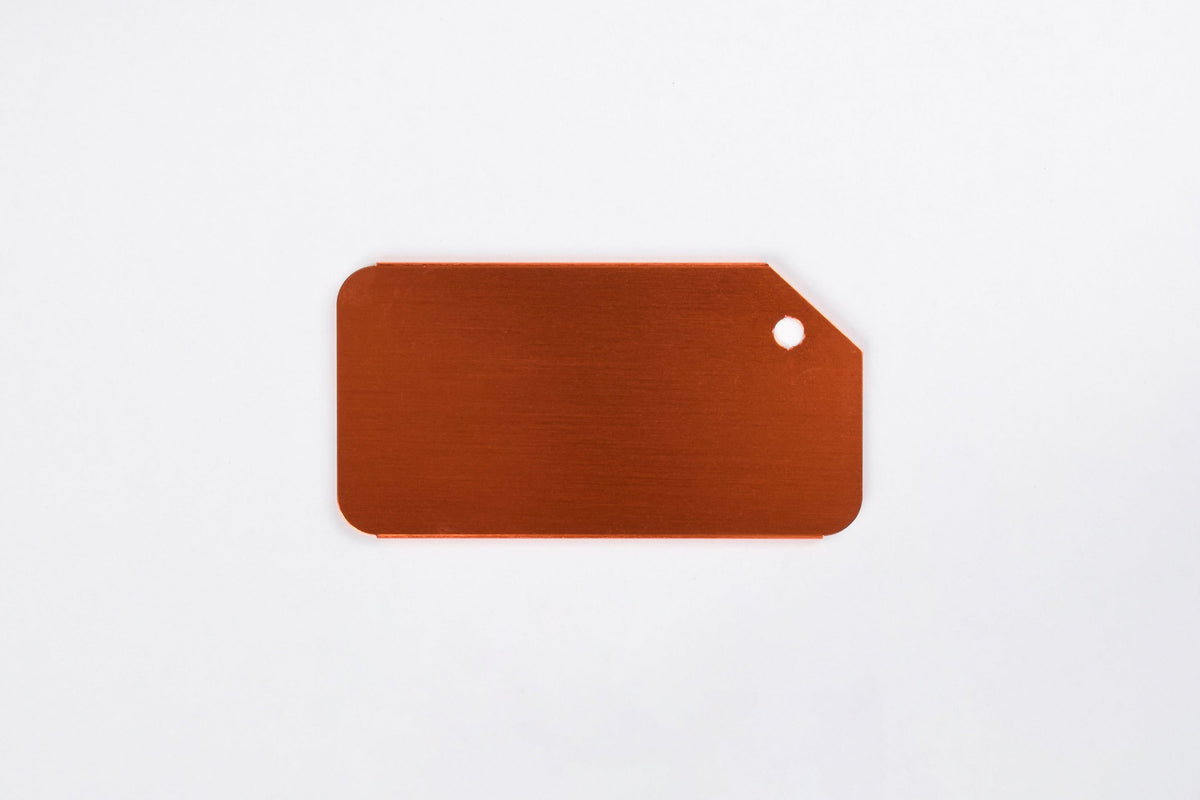 An orange aluminum luggage tag on a white background