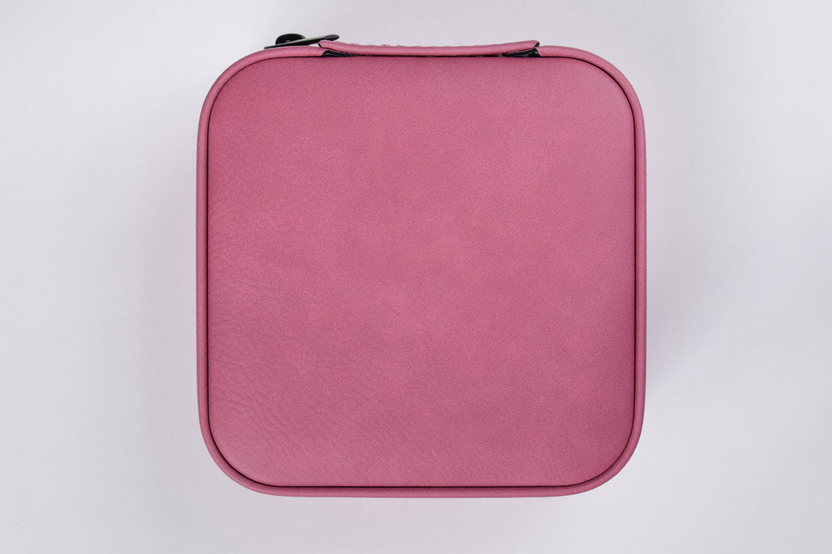 A pink synthetic leatherette travel jewelry box against a white background