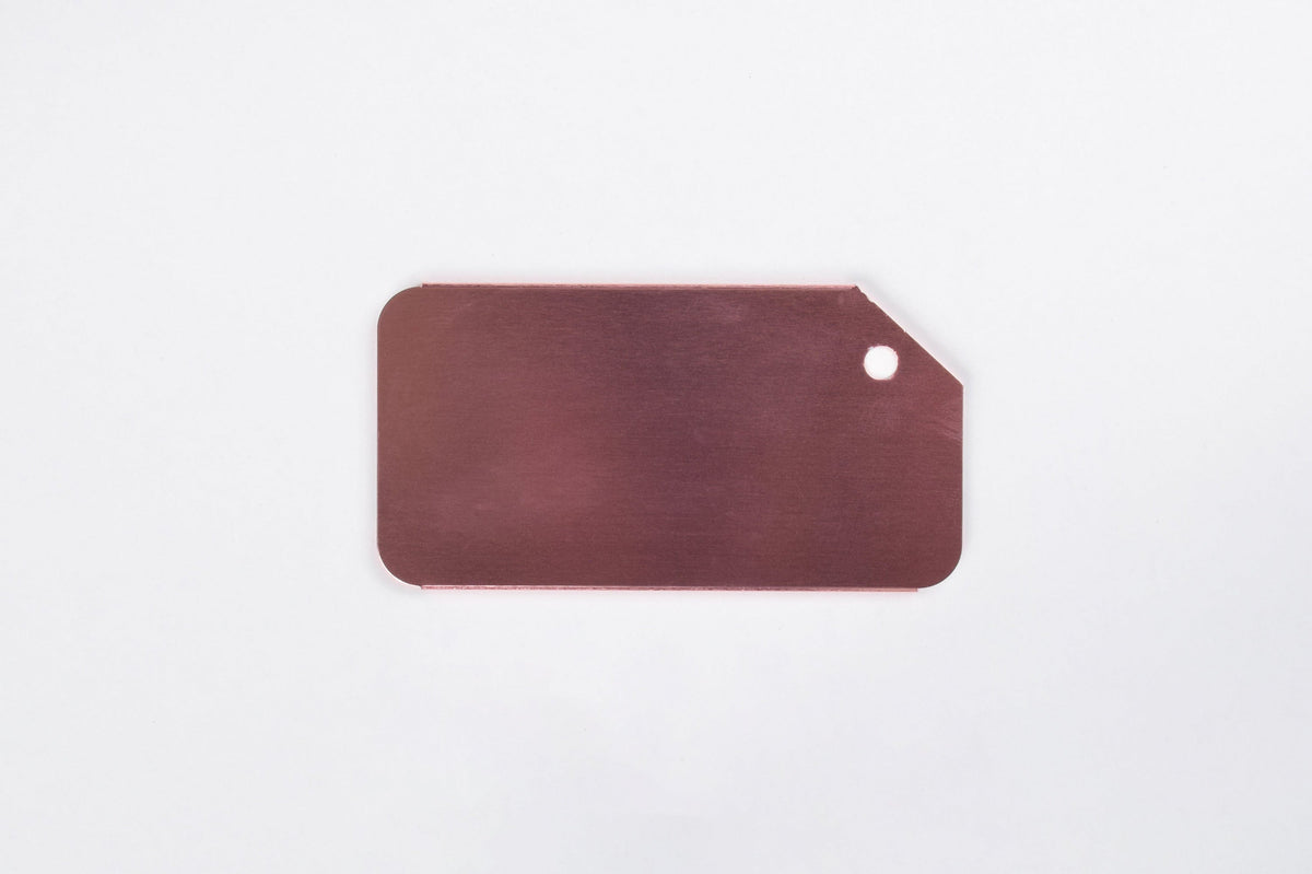 A rose gold aluminum luggage tag on a white background