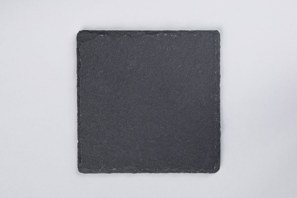 A square slate coaster with a black color against a white background