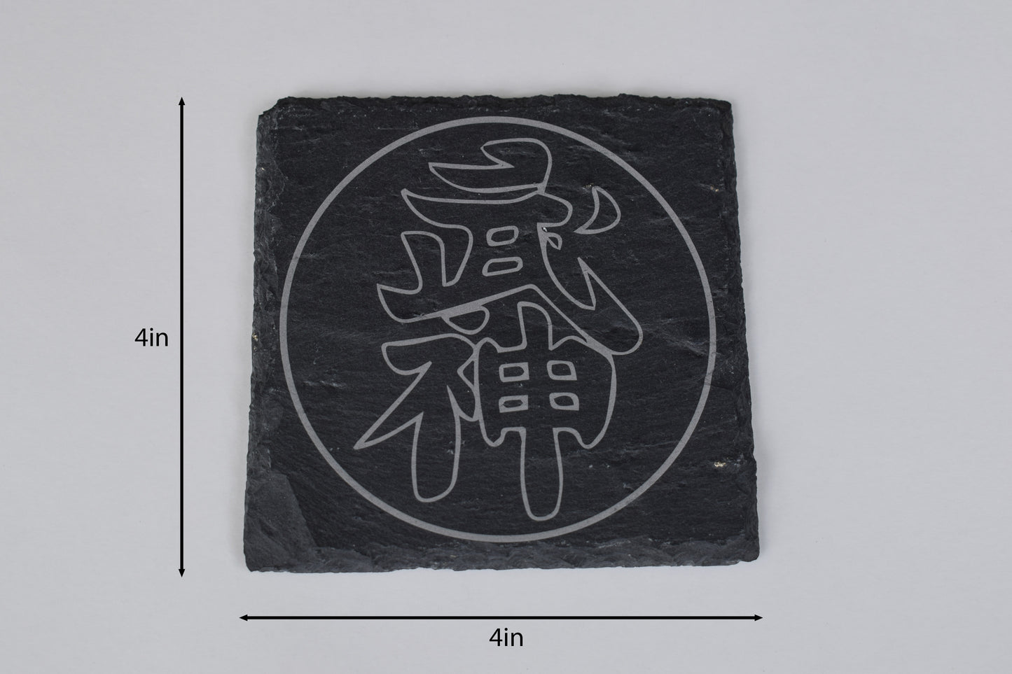 a square coaster made of black slate with a japanese symbol laser engraved in the center, placed on a white background with size markers