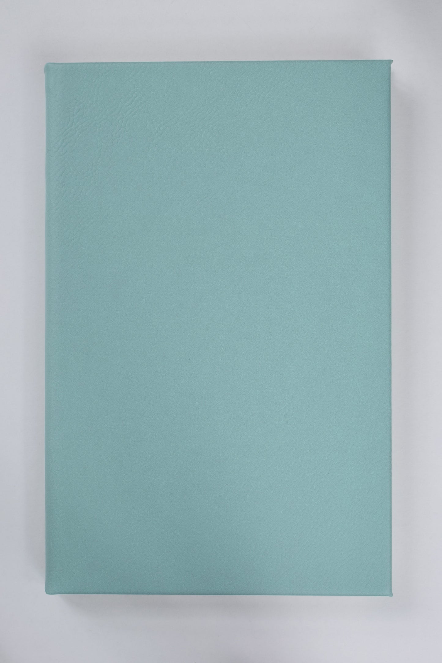 a teal leatherette journal lying on a white surface