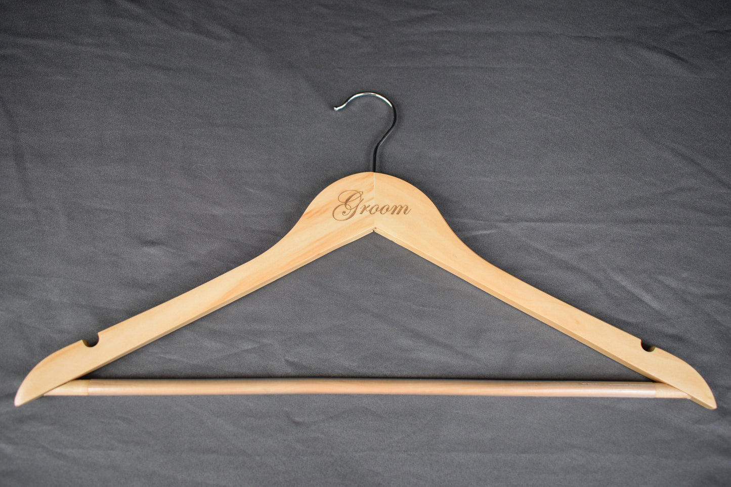 a wooden hanger with "groom" laser engraved on the front
