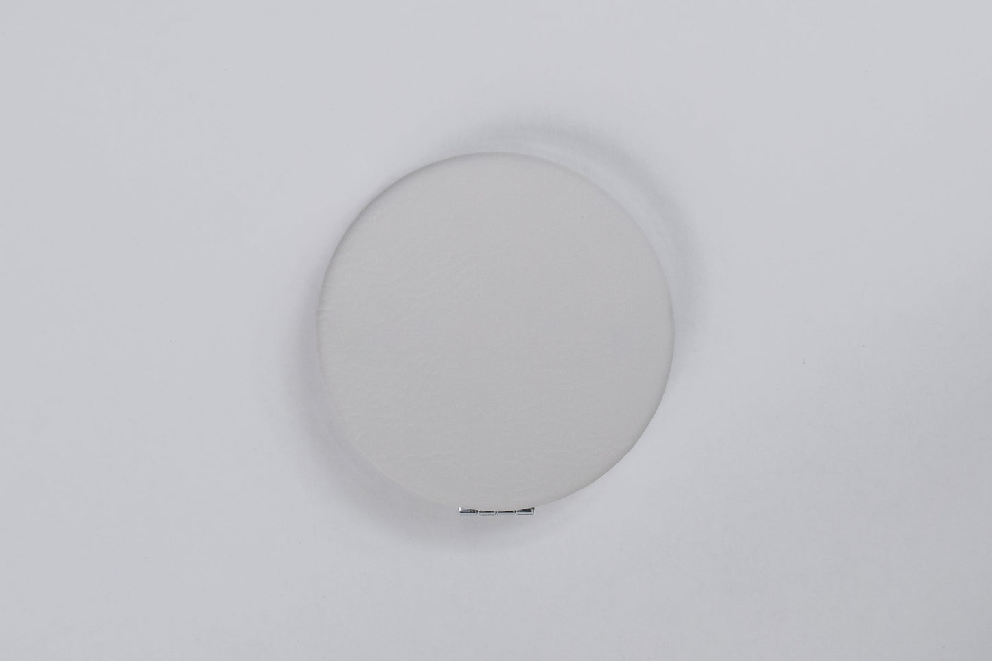 a compact mirror with a white leatherette cover against a white back ground