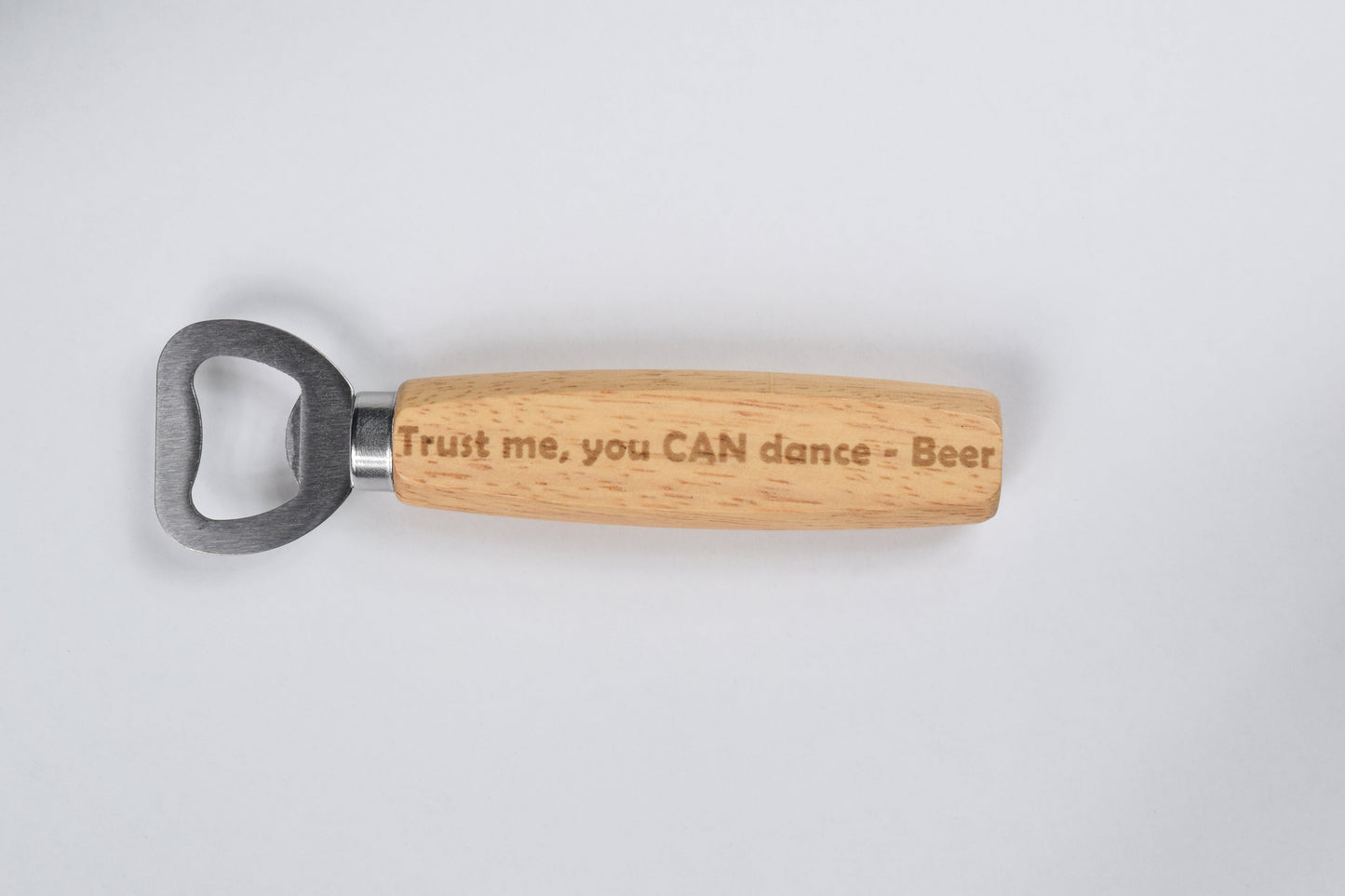 A wood-handle bottle opener with a metal head and a wooden handle that has the text 'Trust me, you CAN dance - Beer' engraved on it.