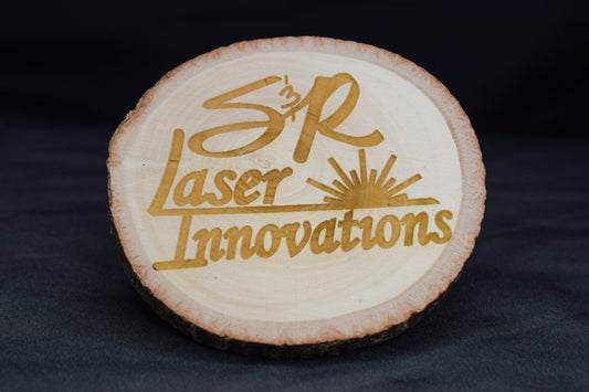 A Basswood wooden coaster with 'SR Laser Innovations' logo and text engraved on it, displayed against a black background.