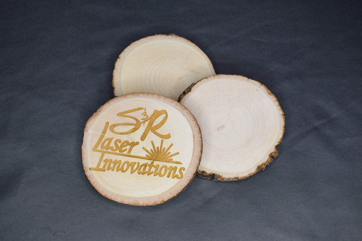 A trio of circular basswood coasters, with on featuring a laser engraving of the 'S&R Laser Innovations' logo