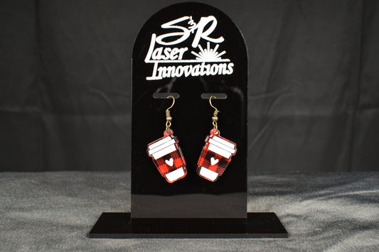 A pair of black and red plaid acrylic earrings with a coffee cup design, displayed on a black stand with the 'S&R Laser Innovations' logo 
