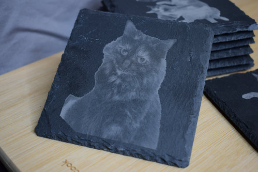 A set of black slate square coasters, showcasing a laser engraved image of a cat