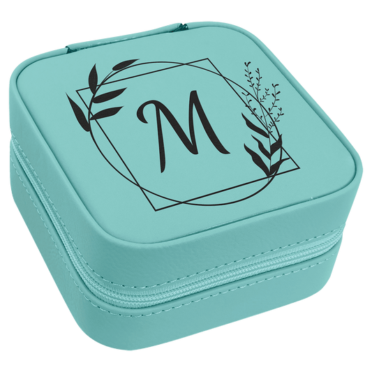 A teal synthetic leatherette travel jewelry box with custom engraving of a letter and leaves on the lid.