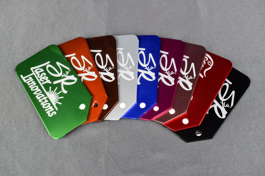 A collection of custom engraved aluminum luggage tags in various colors, each featuring a silver/gray engraved logo