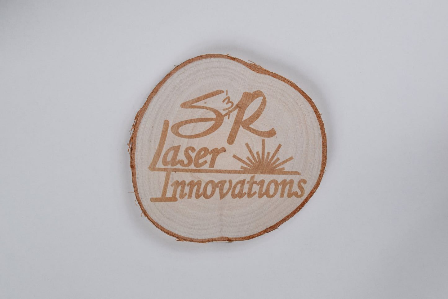 a birch coaster with S&R laser innovations logo engraved on it, against a white background