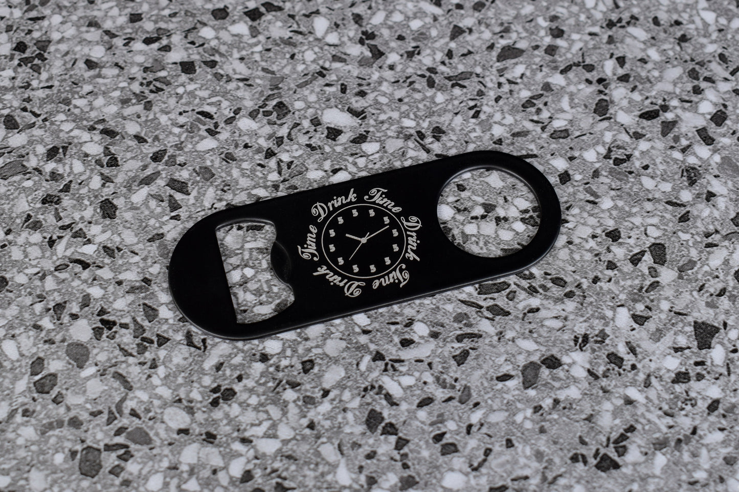 Black bottle opener with text on a textured gray surface