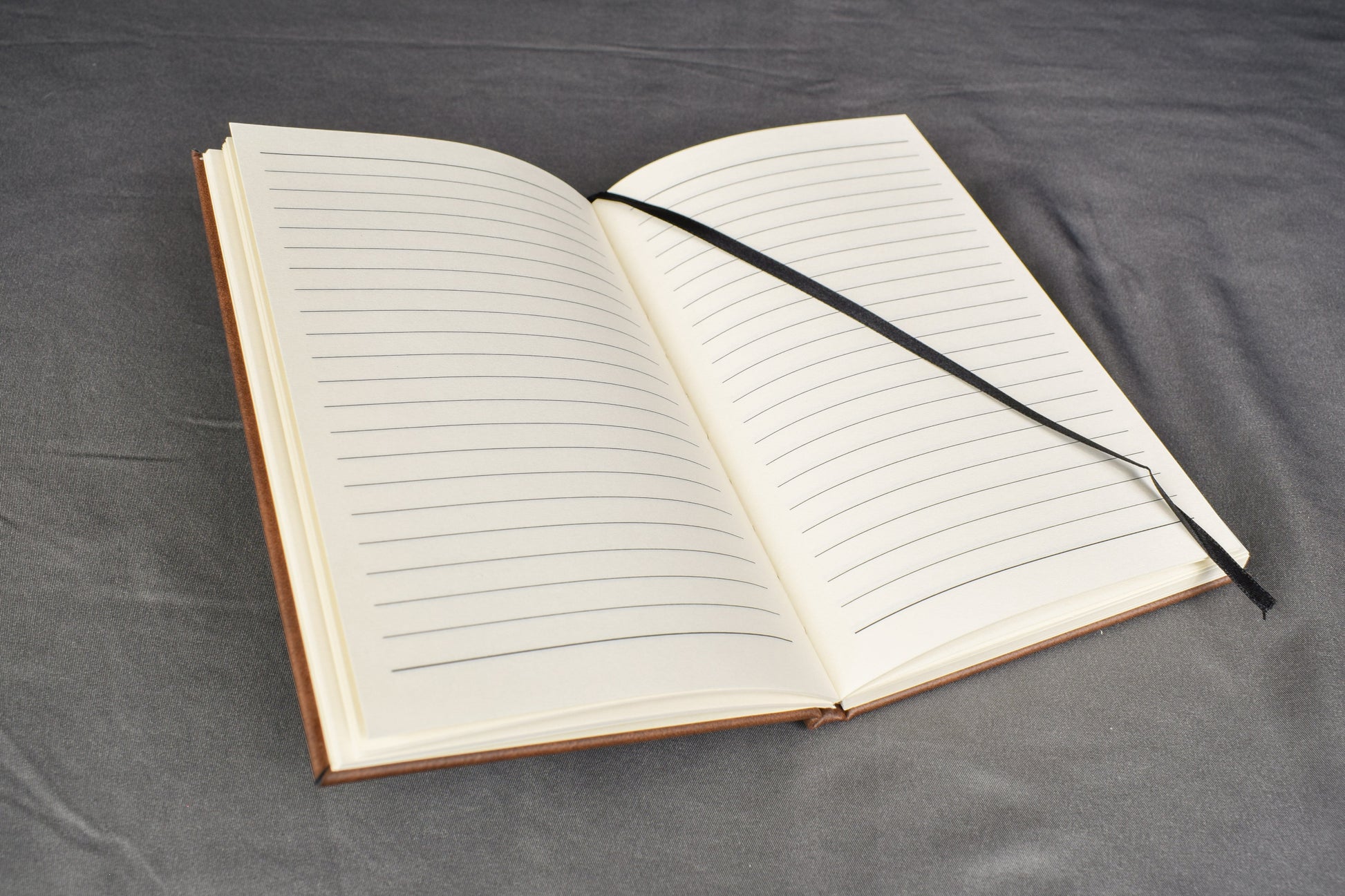 a brown leatherette journal, opened to show the lined pages and ribbon bookmark