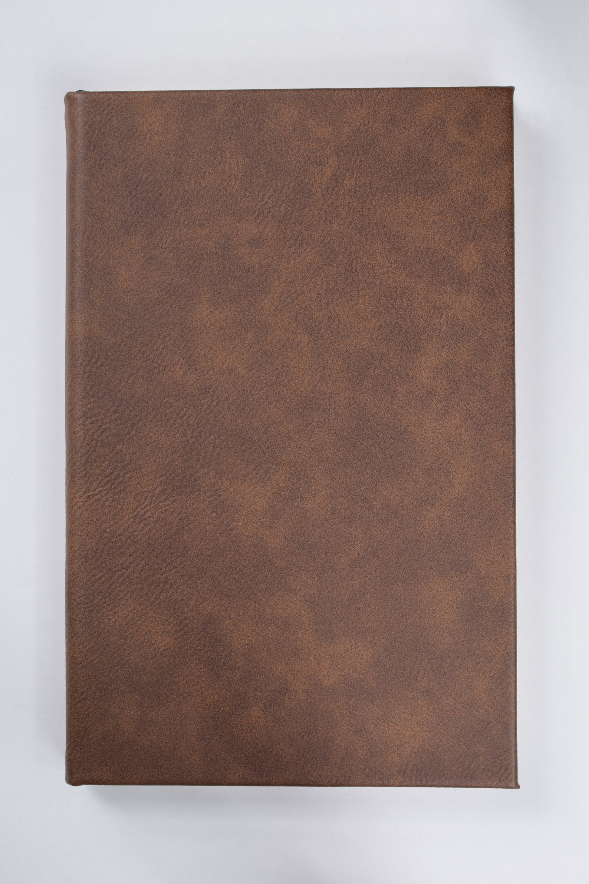 a dark brown leatherette journal lying on a white surface