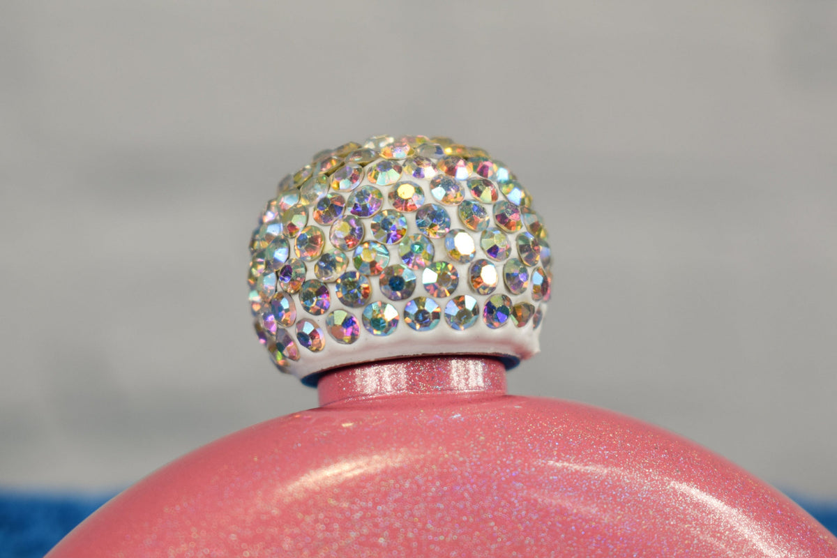 A close up view of the rhinestone cap for pink glittery flask, set against a blurred background