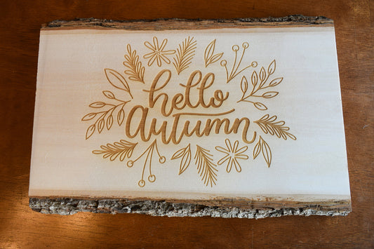 An autumn charcuterie board made of basswood, featuring a fall-themed engraving with leaves, pumpkins, and the text 'Hello Autumn'