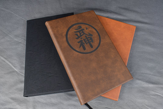 A selection of leatherette journals, available in different colors and featuring a customizable engraved design on the cover.