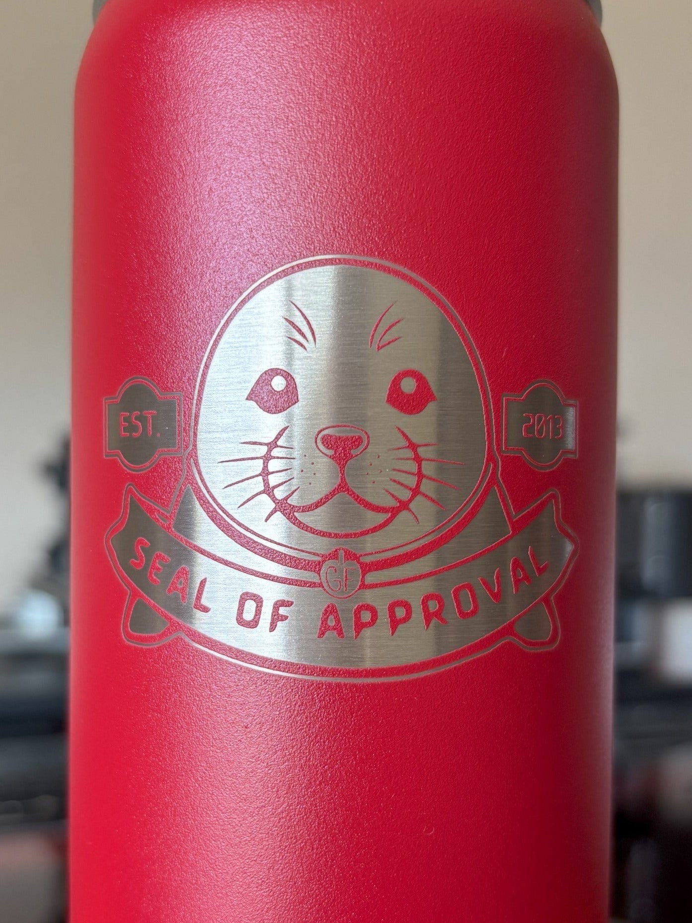 Red bottle with a metallic seal of approval logo on a blurred background