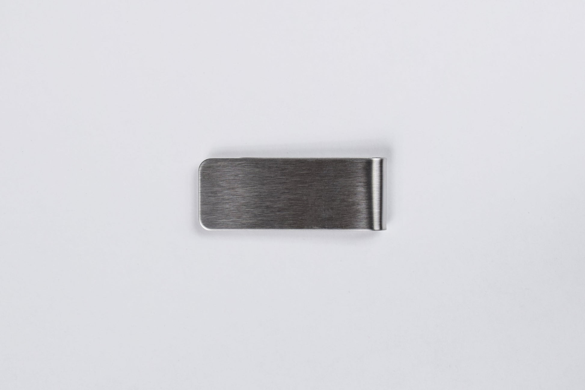 A stainless steel money clip with a brushed finish on a white background.