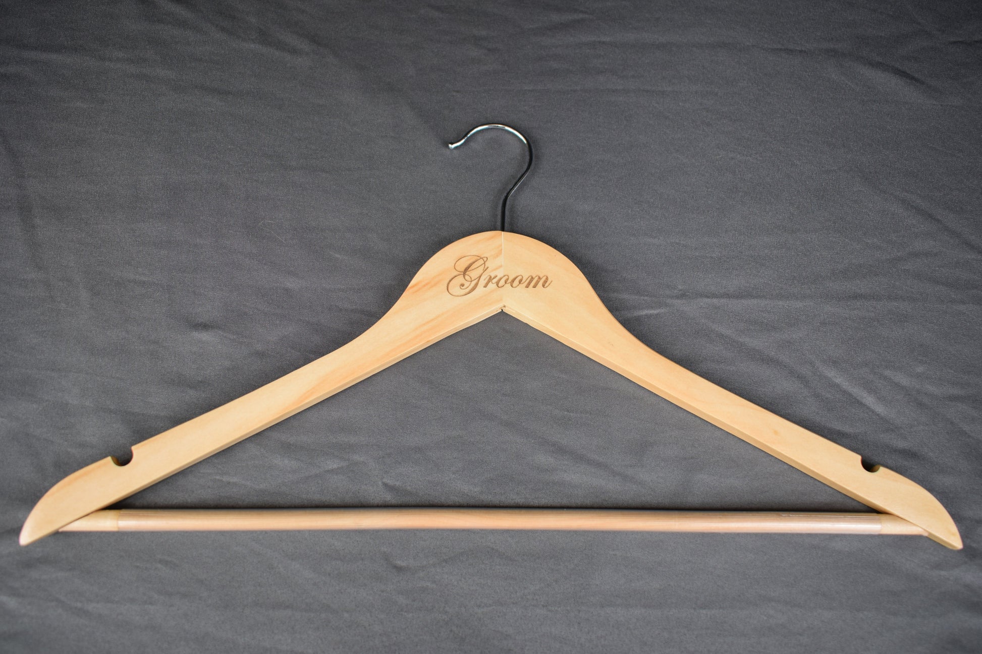 a wooden hanger with "groom" laser engraved on the front