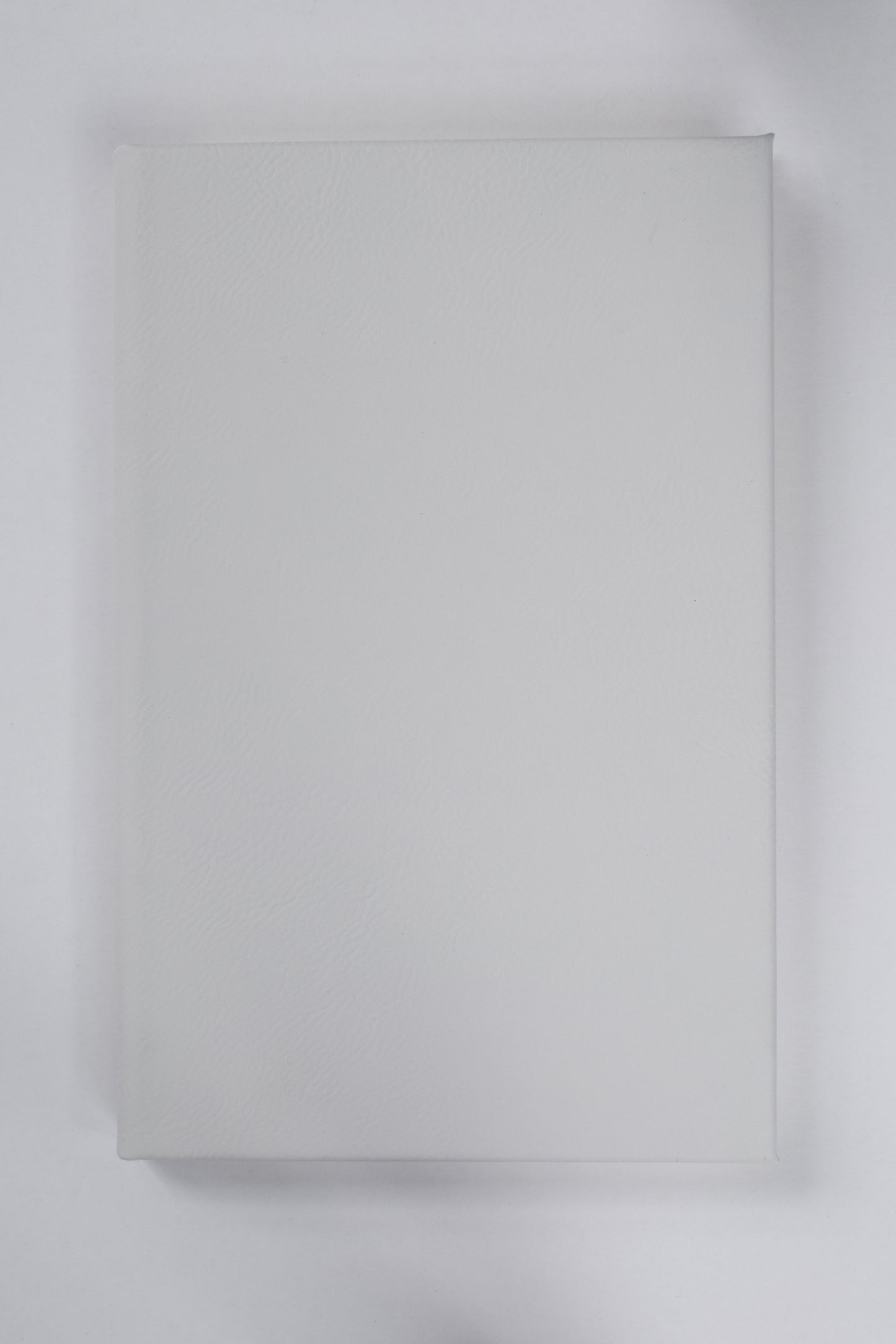 A white leatherette journal lying on a white surface